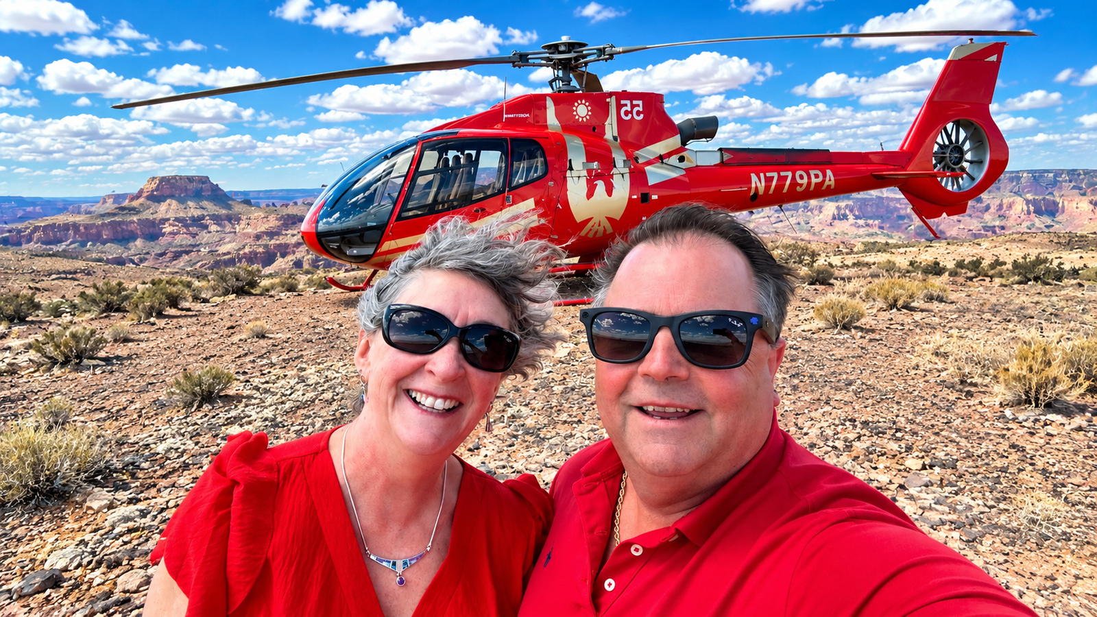 Troy Kane and his wife posing in front of a red helicopter during their Grand Canyon helicopter tour in Arizona.